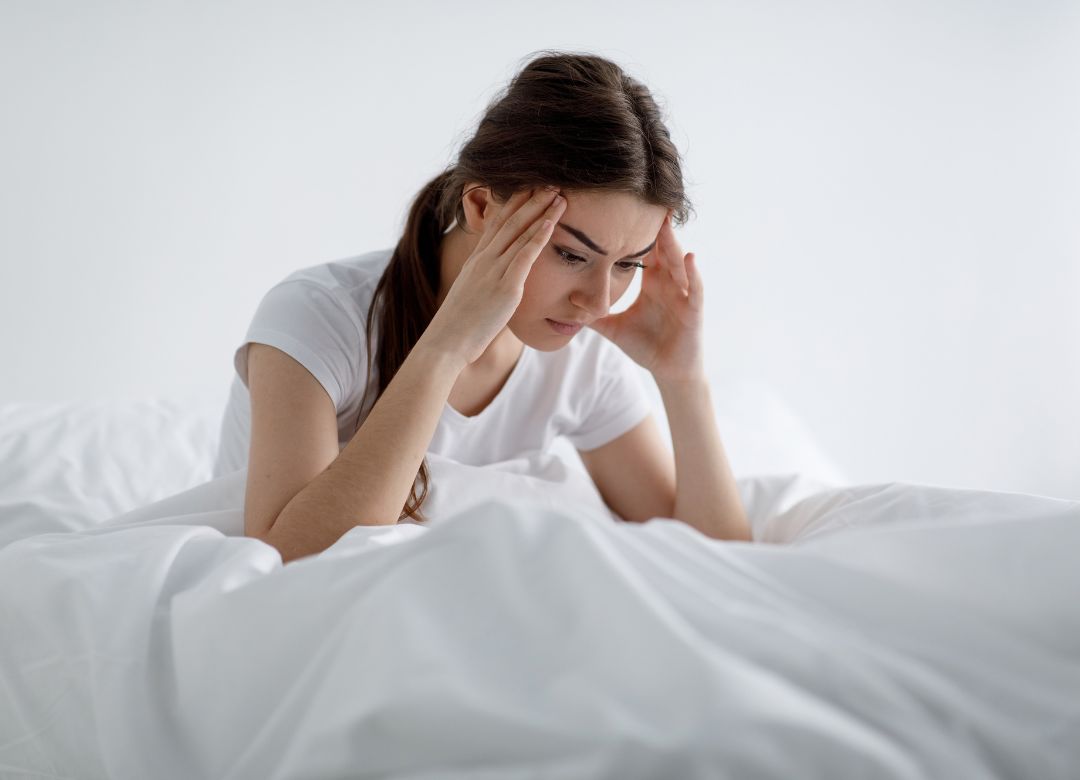 Woman sitting on her bed with concern and feeling stressful without being able to sleep